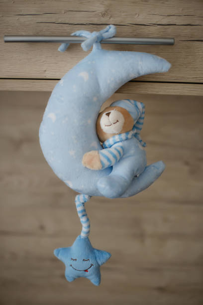 istock Delicate toy featuring a whimsical teddy bear wearing a blue pajama sleeping on a new moon 1171694186