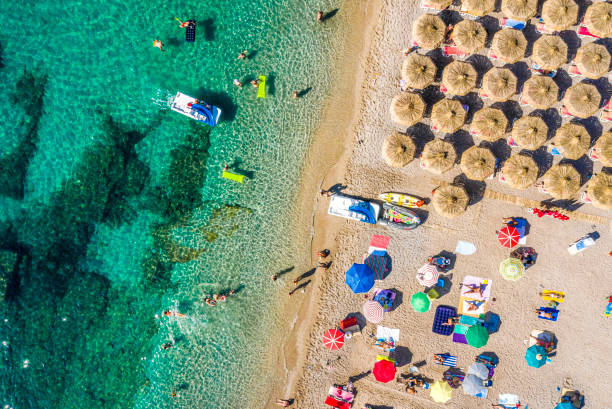 plage de côte de mer verte, avec une plage occupée remplie de parapluies, de transats et de personnes, prises d'un drone au-dessus - mushroom edible mushroom water splashing photos et images de collection