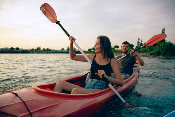 istock Confident young couple kayaking on river together with sunset on the background 1171698433