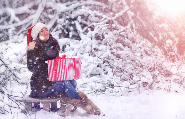 Winter fairy tale, a young mother and her daughter ride a sled in the forest. A girl on a sled with gifts on the eve of the new year in the park. Two sisters walk in a New Year's park and ride a sled with gifts. un cuento de hadas de invierno, una joven madre y su hija montan un trineo en el bosque. una chica en trineo con regalos en la víspera del nuevo año en el parque. dos hermanas caminan en un parque de año nuevo y montan un trineo con regalos.