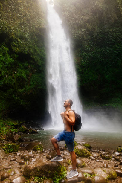 männlicher tourist genießt in der nähe des wasserfalls - bali male beautiful ethnicity stock-fotos und bilder