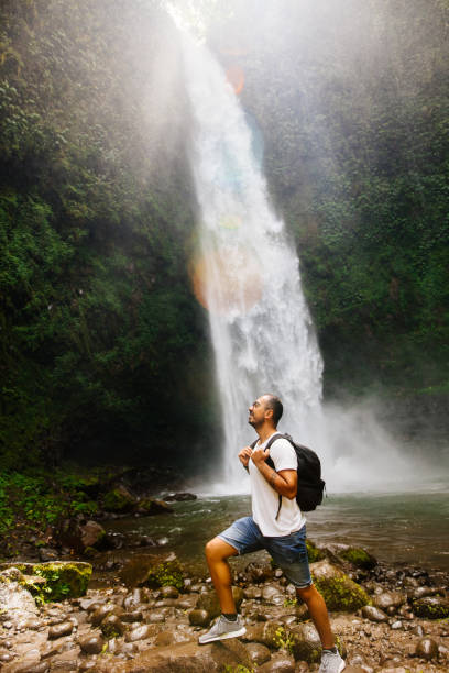 männlicher tourist genießt in der nähe des wasserfalls - bali male beautiful ethnicity stock-fotos und bilder