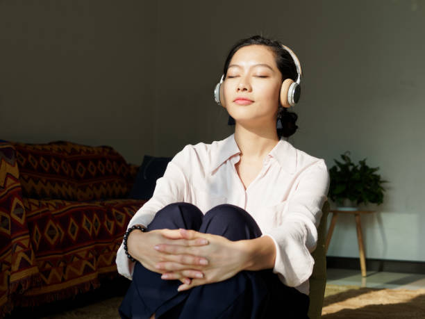 schöne junge brünette frau in weißem hemd sitzen und genießen musik an sonnigen tag zu hause. porträt von glamour chinesischen fröhlichen stilvollen mädchen, emotionen, menschen, schönheit und lifestyle-konzept. - chinese culture china chinese ethnicity human face stock-fotos und bilder