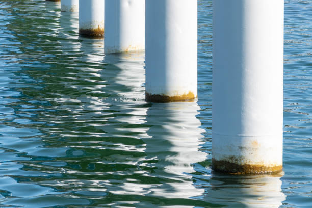 Rusty pier posts in salt sea water. White columns diagonal. Pillars mount for bridge. Sunny weather.