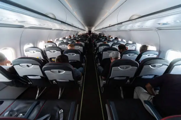 Photo of Airplane cabin seats with passengers. Economy class of new cheapest low-cost airlines without delay or cancellation of flight. Travel trip to another country.