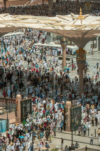 During the Friday prayer thousands of Muslim pilgrims pray at the Al-Masjid an-Nabawī Mosque at the center of the Holy City of Medinah, KSA Medinah, KSA - August 30th 2019: Thousands of people praying outside the mosque in the heat of the desert. Giant parasols are protecting them from the powerful sun. al masjid an nabawi stock pictures, royalty-free photos & images