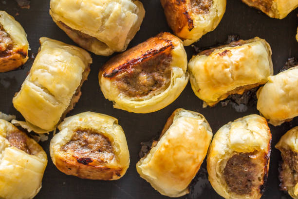 Mini cocktail sausage rolls on baking tin out of oven Mini cocktail sausage rolls on baking tin out of oven - top view savory food photos stock pictures, royalty-free photos & images