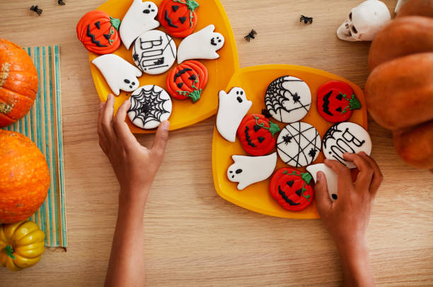 directly above view of unrecognizable boy adjusting gingerbread cookies on plates while preparing sweets for halloween party - breakfast close up studio shot group of objects imagens e fotografias de stock