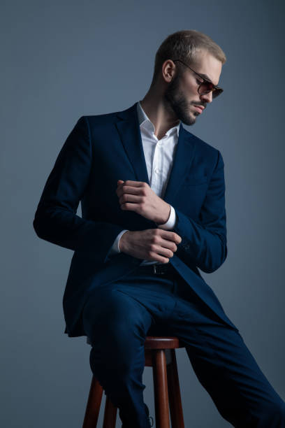 istock seated young elegant businessman fixing his cuffs 1171718568