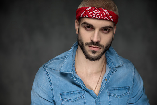 closeup picture of a cool young hipster wearing bandana and jeans shirt looking at the camera