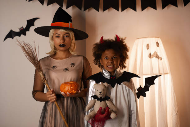 ritratto di famiglia nera in costumi di halloween in piedi contro muro decorato con manichino fantasma e ratti di carta - witch smiling evil bizarre foto e immagini stock