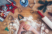 child baking christmas cookies on wooden table