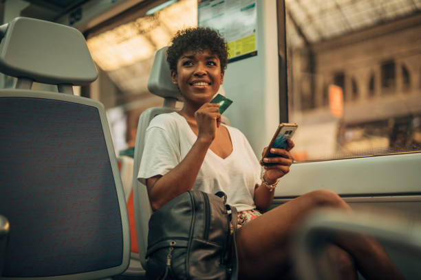 istock Young woman using mobile and holding credit card in train 1171728612