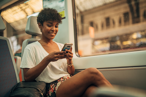 One woman, beautiful young lady riding in train, using mobile phone.