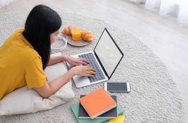 asiatische freiberuflerin arbeitet auf laptop-computer zu hause.frau liegt auf teppich bei brick wall.working online lifestyle.mock up bildschirm mit clipping-pfad - carpet floor lying down people stock-fotos und bilder