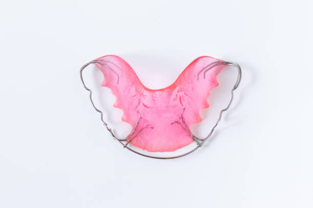 hawley retainer on white background. pink retainer teeths for dental patient.
