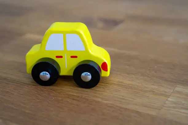 Wooden toy car, yellow, on a brown background.