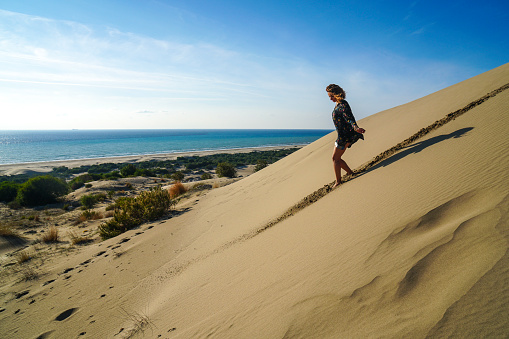 Pretty young woman walking in the sand dunes.