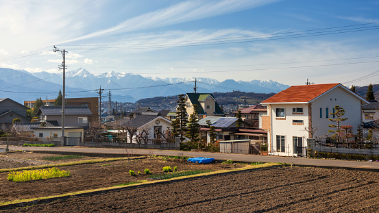 Japanese house village with vegetable farm and central alps mountain against blue sky in Matsumoto, Nagano, Japan.