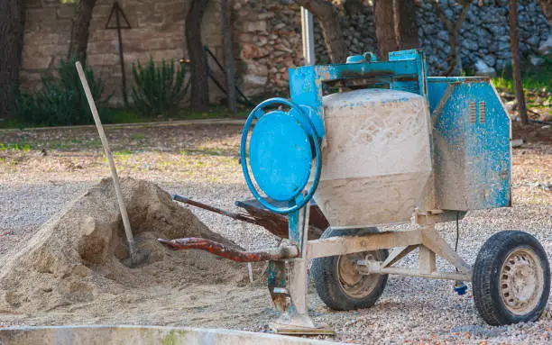 Cement mixer machine at construction site, tools and sand