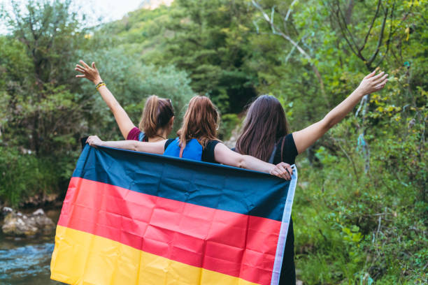 junge frauen in der natur mit deutscher flagge - tag der deutschen einheit stock-fotos und bilder