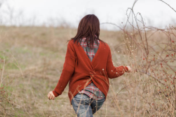 istock Rear view of a woman walking through fields 1171737602