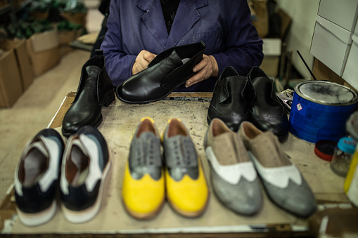 Unrecognizable woman sitting in factory and Polishing oxford shoes and preparing them for sale