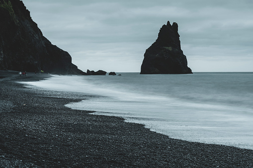 South coast of Iceland near Vik. Black sand on the beach and rock formations. Long exposure photo.