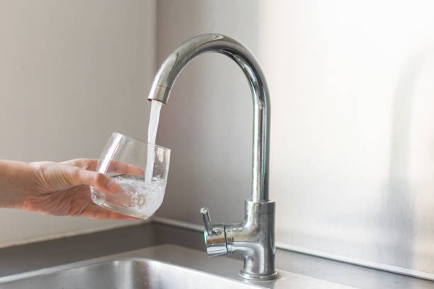 自宅の台所の流しで水のコップを取って台所で手。 - water faucet running water glass ストックフォトと画像