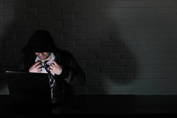 istock Hacker in black mask and hood at the table 1171741416