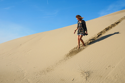 Pretty young woman walking in the sand dunes.