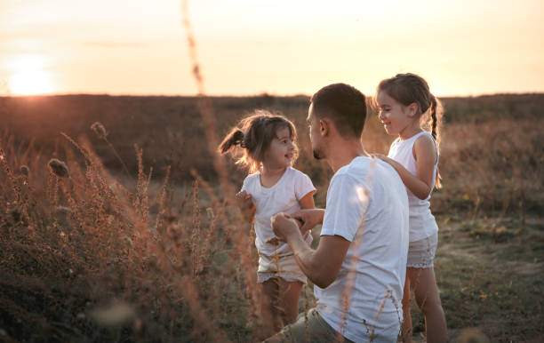 istock Dad and his daughters in the field at sunset . 1171743577