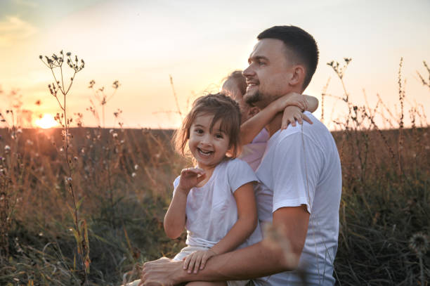 istock Dad and his daughters in the field at sunset . 1171743587