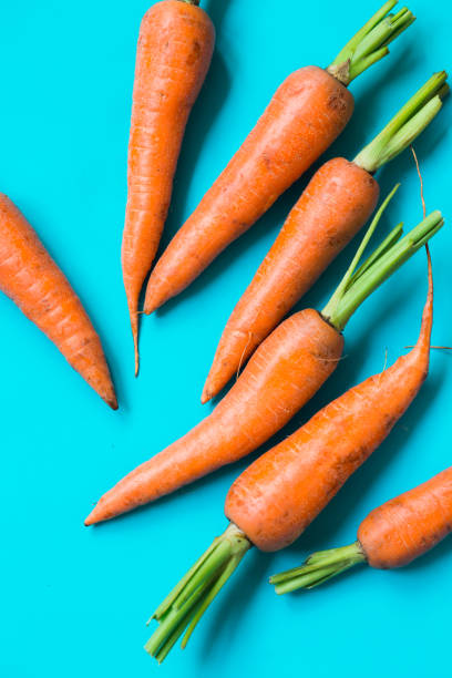 istock A few fresh carrots on blue background. 1171745081