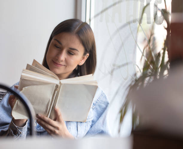 istock Young girl sitting in a cafe and reading a book 1171745103