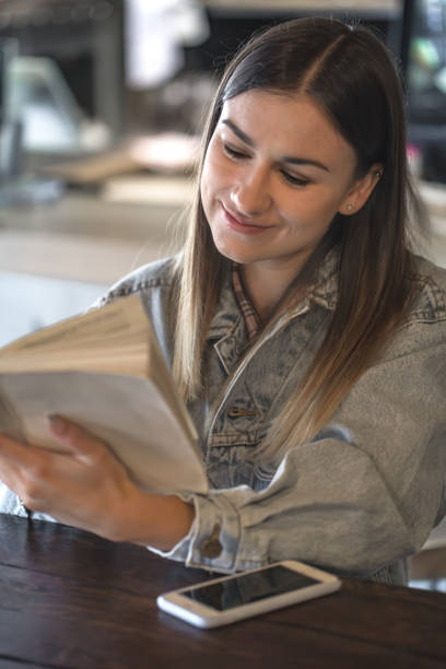 istock Young girl sitting in a cafe and reading a book 1171745120