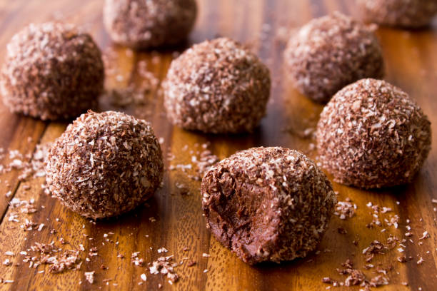 Raw Chocolate Bliss Balls Freshly made soft chocolate orange truffles rolled in shredded coconut chocolate truffle stock pictures, royalty-free photos & images