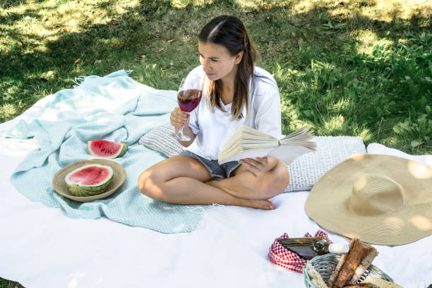 une jeune femme à un pique-nique affichant un livre - women grass glasses e reader photos et images de collection