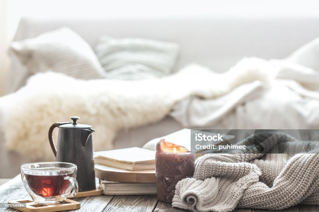 Still life home comfort in the living room Still life home comfort in the living room with a Cup of tea and a kettle , near a burning candle and a knitted sweater.The concept of home atmosphere and comfort Winter Stock Photo