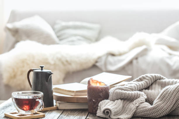 Still life home comfort in the living room Still life home comfort in the living room with a Cup of tea and a kettle , near a burning candle and a knitted sweater.The concept of home atmosphere and comfort tray photos stock pictures, royalty-free photos & images