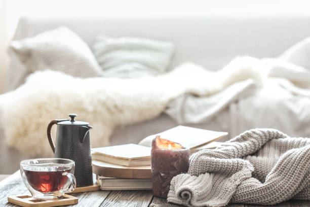 Still life home comfort in the living room Still life home comfort in the living room with a Cup of tea and a kettle , near a burning candle and a knitted sweater.The concept of home atmosphere and comfort cosy stock pictures, royalty-free photos & images