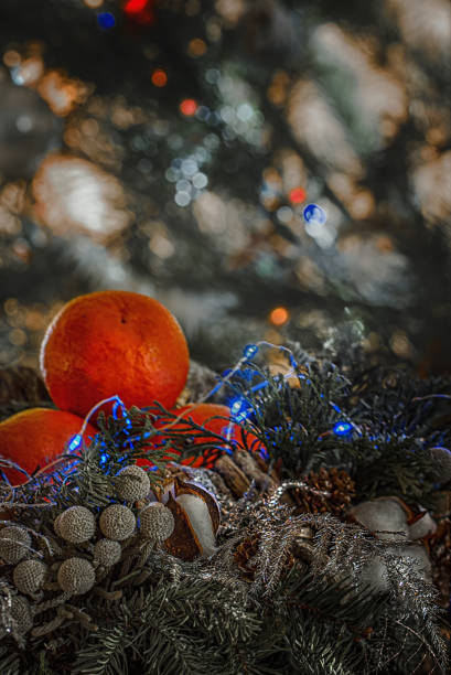 istock Tangerines, cones, pine branches and silver spangles on the background of the Christmas Tree decorated with toys and garlands of colored light bulbs. 1171747731
