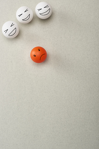top view of balls with cruel and sad face expressions symbolizing victim and abusers on grey background