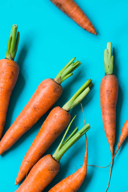 istock A few fresh carrots on blue background. 1171749433