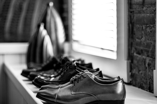 Groom and groomsmen shoes on a window ledge in black and white