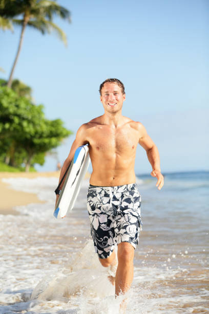 Young man with surfboard walking on the beach