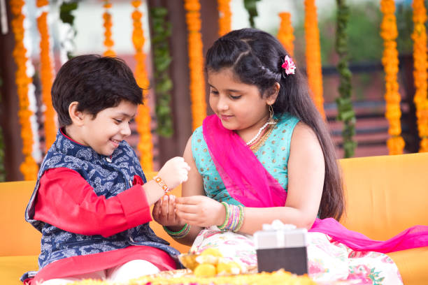 Girl and boy celebrating Raksha Bandhan festival Girl tying rakhi on her brother's wrist on the occasion of Raksha Bandhan festival raksha bandhan stock pictures, royalty-free photos & images