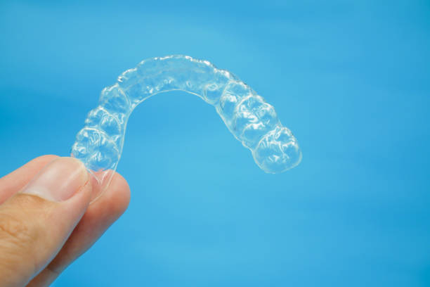 istock hand is holding clear plastic retainer teeth on blue background 1171763720