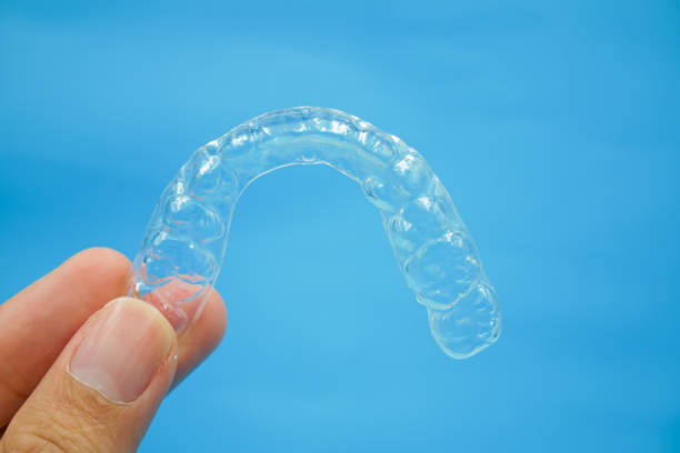 istock hand is holding clear plastic retainer teeth on blue background 1171763730