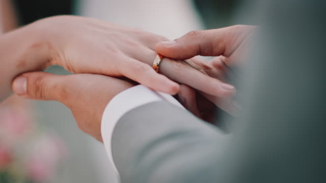 Bridegroom exchanging wedding ring with bride